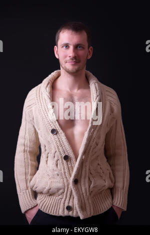 Portrait d'un beau jeune homme dans un chandail, fond noir Banque D'Images