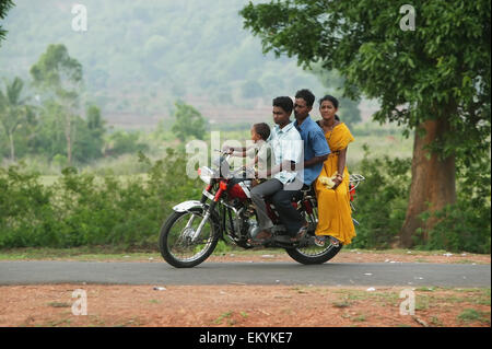 Une famille sur une moto sur une route ; Kharigoda Giajapati Village, District, Orissa, Inde Banque D'Images