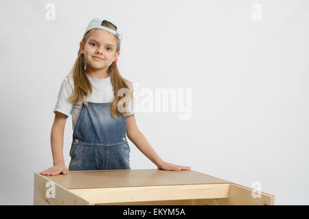 Fillette de six ans à l'affiche et la collecte de l'armoire en bois Banque D'Images