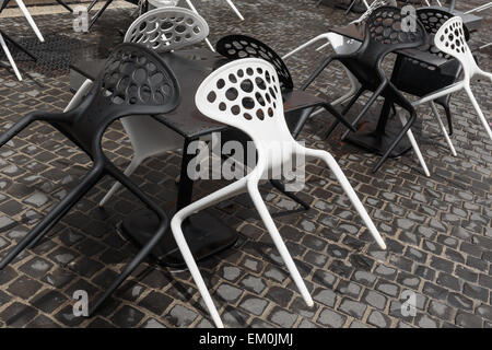 Des chaises en plastique noir et blanc dans un café de la rue après la pluie en Italie Banque D'Images