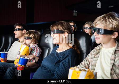 Les familles souriant le visionnage en 3D movie Banque D'Images