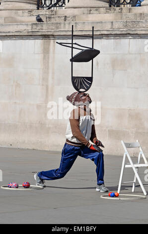 Londres, Angleterre, Royaume-Uni. Artiste de rue à Trafalgar Square, l'équilibre entre une chaise sur la tête Banque D'Images