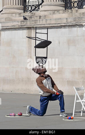 Londres, Angleterre, Royaume-Uni. Artiste de rue à Trafalgar Square, l'équilibre entre une chaise sur la tête Banque D'Images