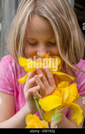 Girl smelling iris fleurs jaune Banque D'Images