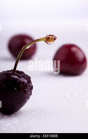 baies de cerises fraîches avec gouttes d'eau sur une bouteille verte ...