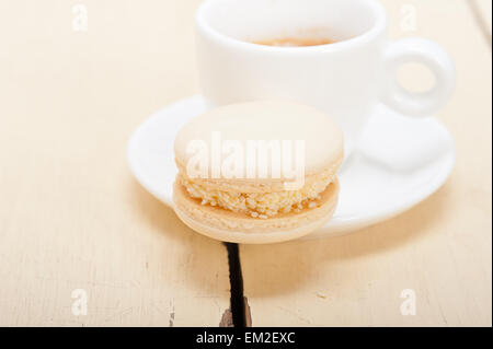 Macarons colorés avec une machine à expresso sur table en bois blanc Banque D'Images
