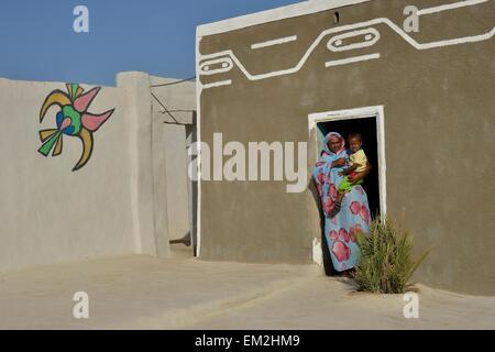 Femme transportant tout-petit, peint en couleurs maison du village nubien dans Umogaal Dongola, Nubie, Soudan Banque D'Images