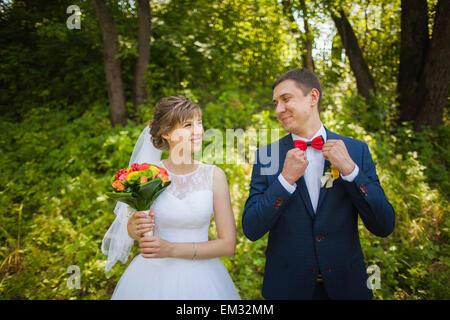 Heureuse mariée, groom standing dans parc verdoyant, à l'embrasser, sourire, rire, Faire place au jour de mariage en amoureux. Banque D'Images