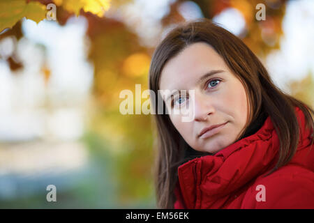 Close-up portrait of a young woman sur un arrière-plan flou lumineux colorés du feuillage de l'automne. Profondeur de champ. L'accent sur e Banque D'Images