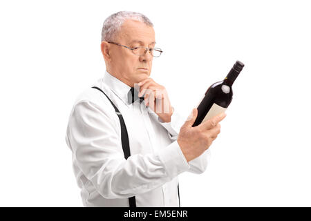 Les élégantes avec des lunettes la lecture de l'étiquette sur une bouteille d'un vin rouge isolé sur fond blanc Banque D'Images