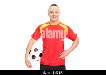 Joueur de football dans une chemise rouge et jaune tenant une balle, souriant et regardant la caméra isolé sur fond blanc Banque D'Images