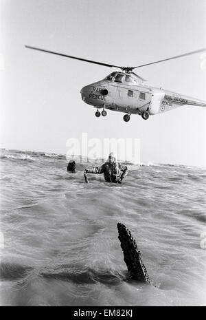 Navigateur maître Colin Walsh de la RAF Air Sea Rescue Service est à la hauteur de la taille dans l'eau sur un banc de sables bitumineux à Goodwin, tout près de la côte de Ramsgate, suite à la découverte d'un bombardier Lancaster de la RAF qui n'a pas réussi à rendre à la maison de sa mission dans la seconde guerre mondiale. Les hommes de la RAF au service de sauvetage dans le Kent Manston numérisation continuellement les mers et repéré les trois hélices sortant de l'eau, ce qui les conduit à examiner de plus près. Volant au-dessus est un hélicoptère Westland Whirlwind. 6e février 1964. Banque D'Images