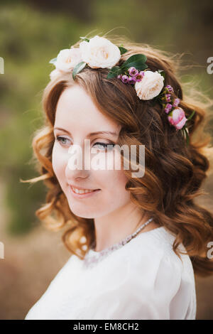 Beautiful woman portrait. fleur couronne en cheveux de mariée. smiley visage féminin. close up of young girl à l'extérieur. Banque D'Images