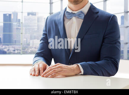 Portrait de l'homme en costume et nœud papillon à table Banque D'Images