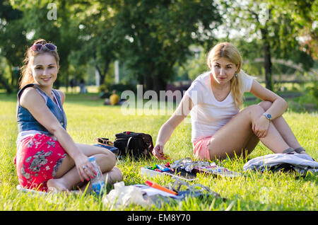 Deux filles sont au repos sur un refroidissement de l'herbe, manger des bonbons et de sourire, regarder un appareil photo Banque D'Images