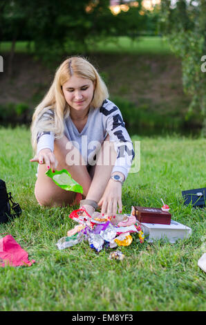 Une fille est effrayant reposant sur une herbe, manger des sucreries et souriante, n'a pas l'air au niveau d'une caméra Banque D'Images