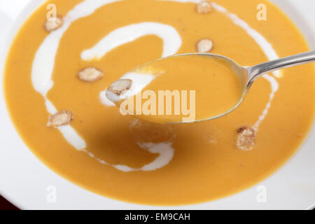 Gros plan sur un spoonfull français traditionnel de soupe à la courge musquée, garnie de crème et de graines de courge grillées Banque D'Images