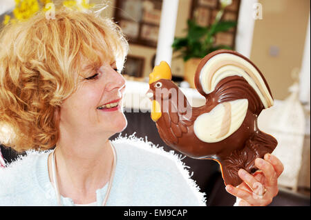 Femme mature manger son grand chocolat au lait Asda coquelet pour Pâques Banque D'Images