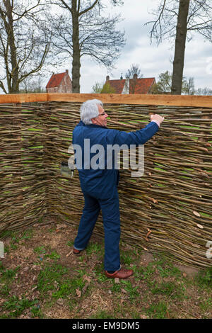 Faire artisan wattle traditionnelles clôtures par des branches de saule mince de tissage Banque D'Images