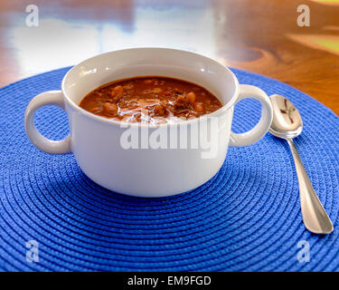 Un bol de chili au bœuf avec des haricots dans un bol blanc bleu sur un napperon. USA Banque D'Images