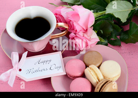 Heureuse Fête des Mères Roses rose en forme de coeur et tasse de thé, de style vintage avec ses macarons sur table en bois de rose en détresse. Banque D'Images