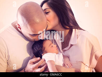 Portrait de famille heureuse, belle jeune parents holding leur mignon adorable bébé nouveau-né, qui s'embrassent Banque D'Images