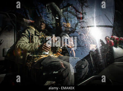 Amsterdam, Pays-Bas. Apr 17, 2015. Youssou (L) attend le départ de son bus pour Amsterdam. Un bus privé a été engagé pour le transport d'un groupe de 50 demandeurs d'asile qui se sont vu refuser des permis et qui ont été retirés de leur lieu de résidence, un vieux garage abandonné,. Credit : Willem Arriens/Alamy Live News Banque D'Images