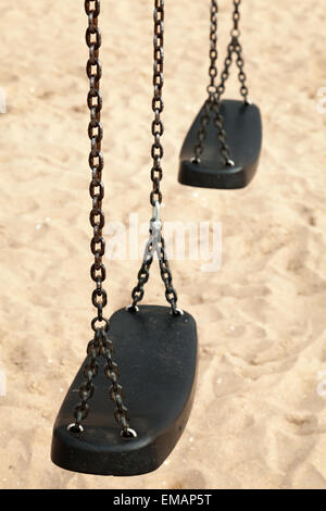 Balançoires vides en plastique noir et acier chaînes sur une plage de sable fin, photo gros plan avec mise au point sélective et peu profondes 6 Banque D'Images