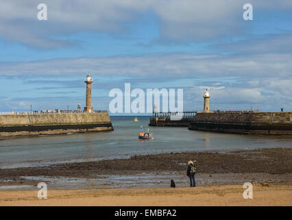 Une femme se tient avec son chien sur la plage, dans le port de Whitby, North Yorkshire, Angleterre. Le 18 avril 2015. Banque D'Images