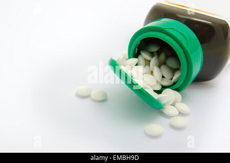 Les petites pilules blanches s'échappant d'une bouteille verte Banque D'Images