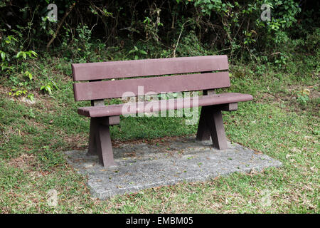 C'est une photo d'un banc public dans un jardin ou parc. Il n'y a personne assis sur elle. C'est piscine en plein air ou à l'extérieur. Il est en bois Banque D'Images