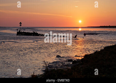 Ruisseau de Faversham, Kent, UK. 20 avril 2015 : Météo France. Une lueur jaune- rouge comme le soleil se lève sur une épave dans Faversham Creek près de l'estuaire de Swale comme la marée se retire. Météo ensoleillée va dominer dans le sud-est pour les prochains jours, mais toujours avec une brise fraîche NE Banque D'Images