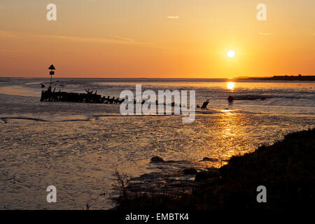 Ruisseau de Faversham, Kent, UK. 20 avril 2015 : Météo France. Une lueur jaune- orange comme le soleil se lève sur une épave dans Faversham Creek près de l'estuaire de Swale comme la marée se retire. Météo ensoleillée va dominer dans le sud-est pour les prochains jours, mais toujours avec une brise fraîche NE Banque D'Images