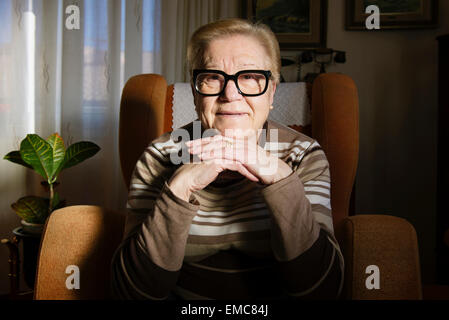 Portrait of happy femme âgée assise sur le fauteuil Banque D'Images