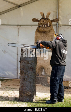 L'homme en utilisant une scie à découper les statues de troncs d'arbres Banque D'Images