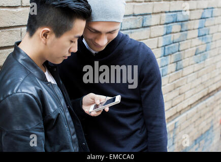 Chine, Hong Kong, jeune homme gay couple standing in street looking at smartphone Banque D'Images