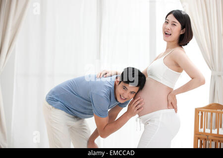 Le jeune père caressa le ventre enceinte pour écouter le fœtus Banque D'Images