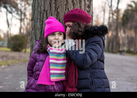 Dit une autre fille fille un secret dans un parc par une journée d'hiver Banque D'Images