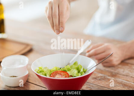 Les mains de l'assaisonnement dans un bol à salade Banque D'Images