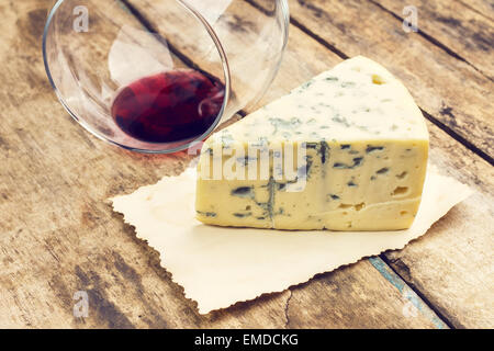 Fromage bleu avec verre de vin renversé sur la table en bois. Arrière-plan de menu Restaurant vintage. Les tons de couleurs chaudes de droit Banque D'Images