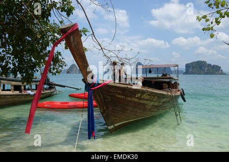 Un touriste bateau longtail amarré avec des kayaks sur une plage de Koh Hong dans la mer d'Andaman au large de la province de Krabi en Thailande Banque D'Images