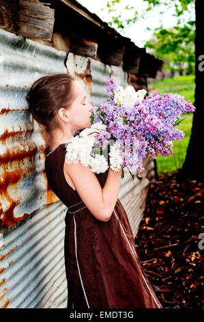 Girl smelling bouquet de lilas par barn Banque D'Images