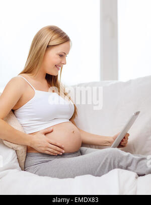 Smiling pregnant woman with tablet PC ordinateur Banque D'Images