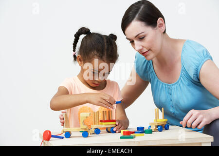 Professeur et élève préscolaire jouer avec maison en bois Banque D'Images