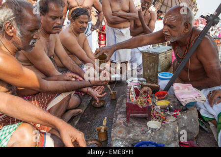 Un Pandit (prêtre et saint homme qui accomplit des cérémonies) mène des puja (prière) avec les pèlerins et les dévots sur les ghats à Varanas Banque D'Images