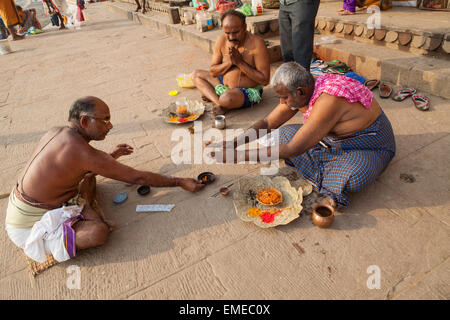 Un Pandit (prêtre et saint homme qui accomplit des cérémonies) mène des puja (prière) avec les pèlerins et les dévots sur les ghats à Varanas Banque D'Images