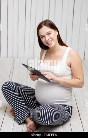 Smiling pregnant woman using tablet computer Banque D'Images