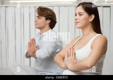 Pregnant woman practicing yoga avec son mari Banque D'Images