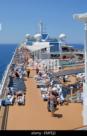 Vue sur les bains de soleil et la terrasse de la piscine d'un paquebot de croisière pendant une journée chaude et ensoleillée en mer en croisière sur la mer Méditerranée Banque D'Images