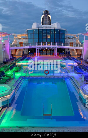 L'éclairage d'inondation on cruise ship plage de piscine à la fin de la journée avec des passagers sous le pont pour le repas du soir (pour voir de jour voir Alamy info le bord) Banque D'Images
